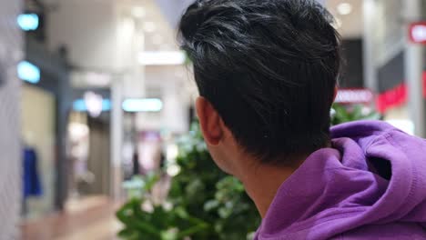 Young-Asian-man-sitting-in-shopping-mall-and-smile,-close-up-view