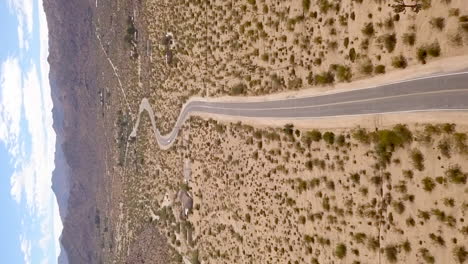 The-Mojave-Desert-road-leading-to-Joshua-Tree-National-Park,-California---aerial-vertical-orientation
