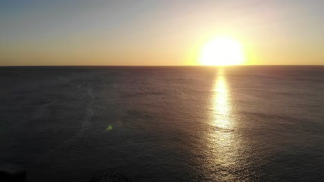 Aerial-View-Of-Golden-Yellow-Sunset-Over-The-Ocean-Water-Towards-Horizon
