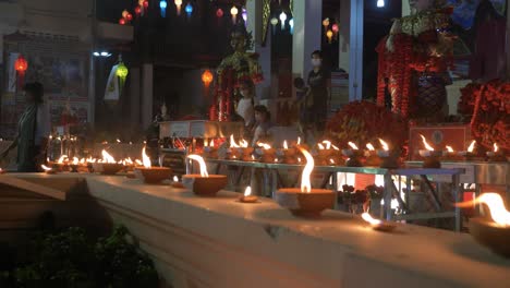 Unzählige-Traditionelle-Und-Heilige-Kerzen-Brennen-Nachts-Vor-Dem-Buddhistischen-Tempel,-Während-Die-Gläubigen-Nach-Dem-Gebet-Gehen
