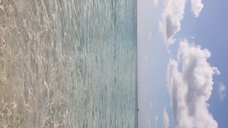 Vertical-video,-low-angle-view-of-turquoise-Caribbean-water-on-famous-Seven-Mile-Beach-in-Grand-Cayman,-Cayman-Islands