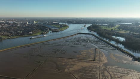Luftaufnahme-Von-Wattflächen-In-Der-Nähe-Eines-Flusses-Mit-Boots--Und-Schiffsverkehr-An-Einem-Sonnigen-Tag-In-Den-Niederlanden