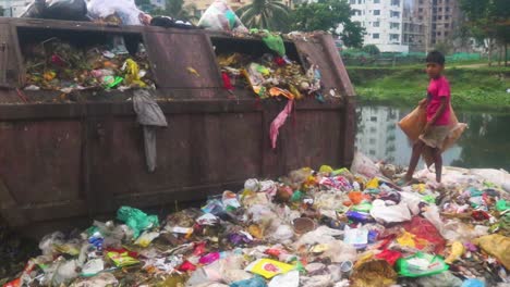 Un-Niño-Trabajador-Recoge-La-Basura-En-Un-Vertedero-En-Dhaka,-Bangladesh,-En-Busca-De-Materiales-Reciclables-Como-Trapero