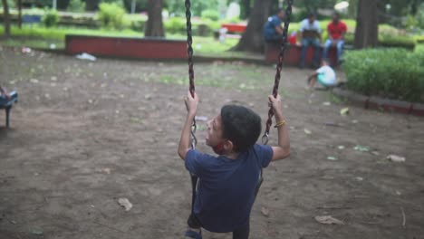Child-playing-on-a-swing-in-slow-motion-in-a-park