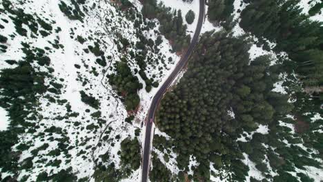Car-driving-on-road-through-forest-in-snow-landscape