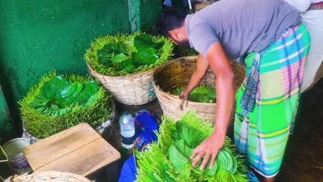A-Betel-leaf-vendor-in-Asia-is-stacking-leaves-for-sale,-showcasing-the-local-street-food-culture