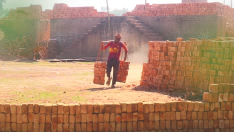 A-brick-worker-carries-two-piles-of-newly-made-bricks,-showcasing-hard-work-and-craftsmanship