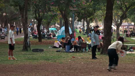 Fröhliche-Chinesische-Teenager-Spielen-Am-Wochenendenachmittag-Frisbee-Im-Städtischen-Innenstadtpark