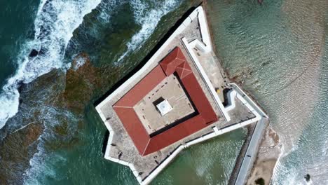 Rotating-bird's-eye-top-aerial-drone-shot-of-the-historic-star-shaped-Reis-Magos-fort-with-waves-crashing-into-the-white-walls-in-the-beach-capital-city-of-Natal-in-Rio-Grande-do-Norte,-Brazil