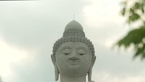 El-Gran-Buda-Phuket-Tailandia-Entre-Hojas-De-Palma-Tiro-Inclinado-Puesta-De-Sol-Nublada