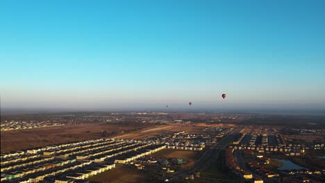 Aerial-view-hot-air-balloons-flying-over-a-neighborhood,-golden-hour-in-Florida,-USA