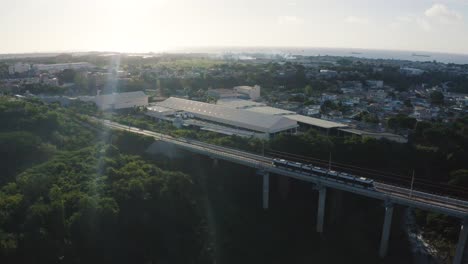 Aerial-view-showing-Modern-metro-driving-on-bridge-during-sunset-time-in-Mauritius,-Africa
