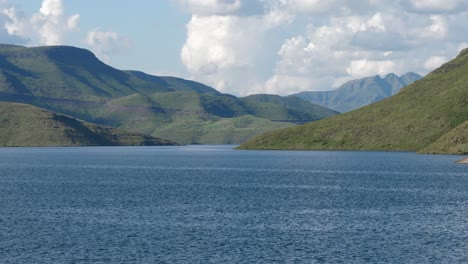 Scenic-static-shot:-Deep-blue-reservoir-lake-in-hilly-landscape,-cloud