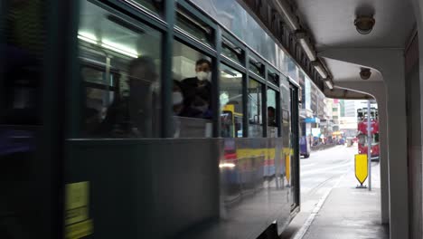 Doppeldecker-Straßenbahnwagen-Fahren-Statisch-An-Einer-Haltestelle-Im-Zentrum-Von-Hongkong-Vorbei