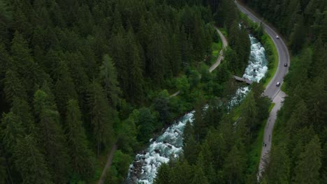 Aerial-drone-bird's-view-of-forest-road-by-Taufers-Castle-river-current,-forward