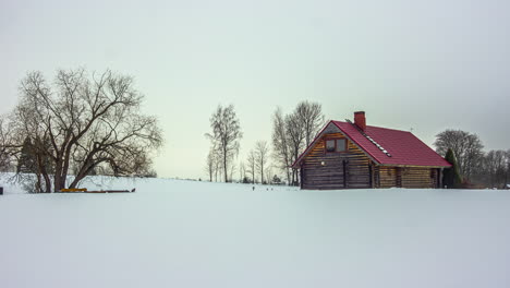 Timelapse-of-cold-and-snowy-landscape-with-a-wooden-house-under-a-cloudy-sky