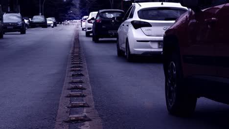 Cars-driving-on-asphalt-road-in-Brazil-in-slow-motion,-desaturated-gloomy-filter-effect