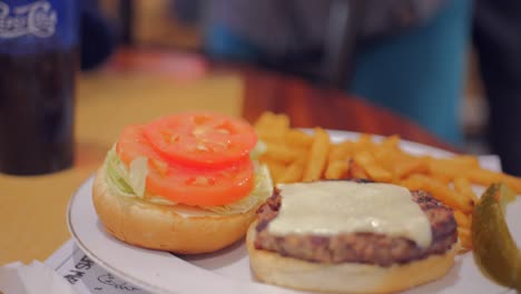 Plate-Of-Juicy-Burger-With-Crispy-Fries-On-The-Side,-Perfect-Combo-Of-Savory-And-Salty-Flavors