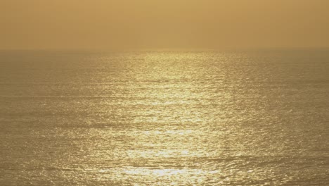 Deep-golden-hour-sunset-with-ocean-reflections-to-the-horizon-line-in-summer