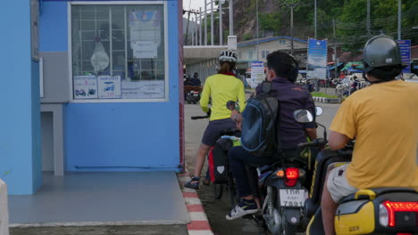 People-on-motorcycles-and-bikes-paying-toll-to-enter-ferry-boat-in-Thailand