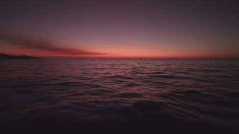 Aerial-Drone-4K-Flyover-Ocean-Waves-With-Colorful-Red-Sunset-On-Horizon