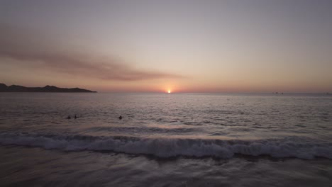 Luftdrohne-über-Menschen-Am-Strand-Mit-Sonnenuntergang-über-Dem-Meereshorizont,-4k