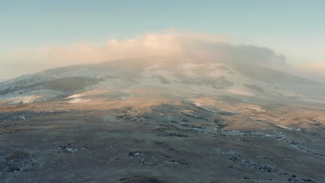 Vista-Aérea-De-La-Cima-De-La-Montaña-Cubierta-De-Serena-Niebla-Matutina