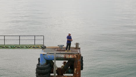 Ein-Südostasiatischer-Mann-Fischt-Friedlich-Von-Der-Ecke-Des-Piers-Und-Geht-Seiner-Leidenschaft-Nach