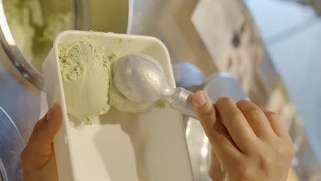 ice-cream-shop-worker-serving-pistachio-ice-cream-in-a-pot-to-take-home