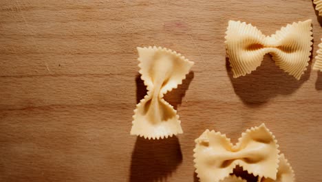 throwing-uncooked-butterfly-pasta-onto-a-wooden-table-close-up-in-studio-lighting