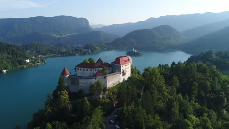 Castillo-En-El-Lago-Sangrado-Eslovenia,-Drone-Aéreo-Sobre-El-Agua-Azul-De-La-Isla,-Colinas-Verdes-Y-Panorama-Escénico-Del-Destino-De-Viajes-Y-Turismo,-Cordillera-De-Los-Alpes-Julianos