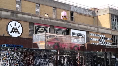Hand-held-shot-of-a-pink-car-in-a-broken-glass-box-with-graffiti-on-the-walls-in-Brick-Lane