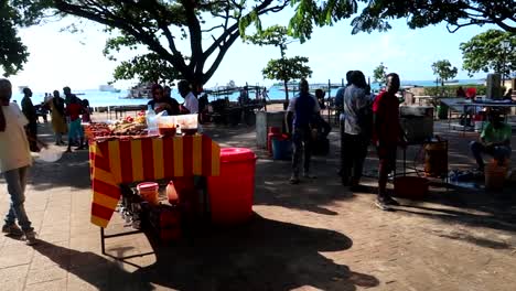 Gente-Local-Tanzaniana-En-Puestos-De-Comida-En-El-Parque-Acercándose-A-Los-Turistas-Para-Vender-Comida-Típica