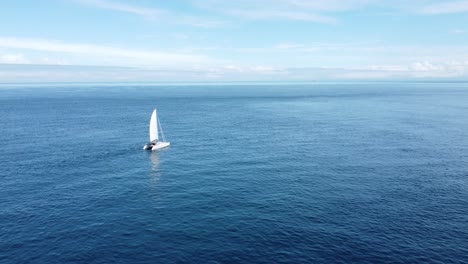 Flying-towards-a-small-yacht-as-it-slowly-sails-through-a-flat-ocean