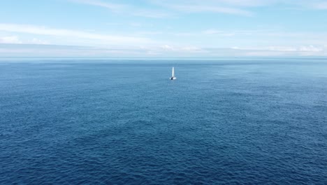 Flying-towards-and-around-a-small-yacht-as-it-slowly-sails-through-a-calm-ocean