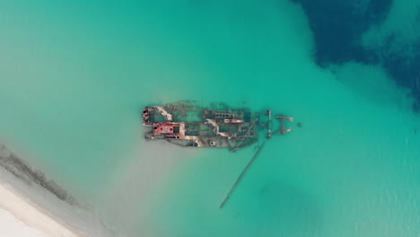 Drone-Video-fast-ascending-overhead-shipwreck-Blue-sea-waters-top-down-view