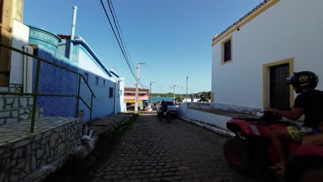 Slow-motion-shot-moving-down-a-small-cobblestone-road-in-the-small-beach-town-of-Barra-de-Cunhaú-in-Canguaretama,-Rio-Grande-do-Norte,-Brazil-with-a-view-of-the-ocean-on-a-summer-day