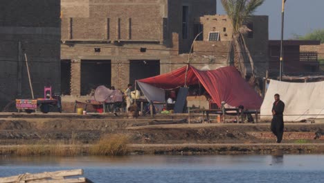 Blick-über-Den-Fluss-Auf-Ein-Provisorisches-Lager,-Das-Von-Einheimischen-Aufgrund-Der-Überschwemmung-In-Sindh,-Pakistan,-Errichtet-Wurde