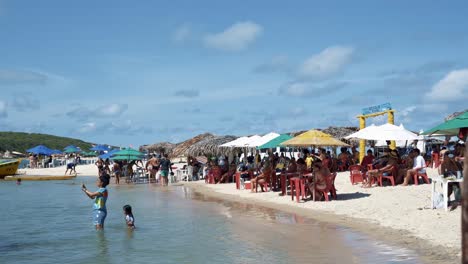 Tilt-up-shot-of-Brazilian-locals-and-tourists-enjoying-the-tropical-Restinga-beach-near-the-famous-Barra-de-Cunhaú-in-the-city-of-Canguaretama-in-the-state-of-Rio-Grande-do-Norte,-Brazil