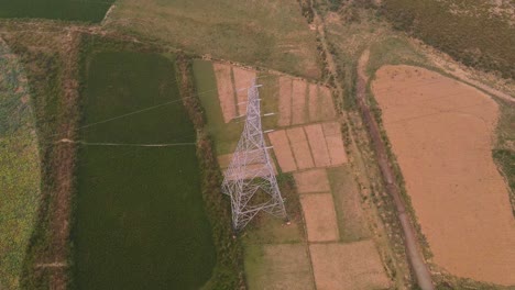 Aerial-view-rising-over-electricity-pylon-on-misty-rural-India-agricultural-farmland