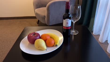 Primer-Plano-Del-Cumplido-Del-Hotel-Con-Fruta-Y-Botella-De-Vino-Tinto