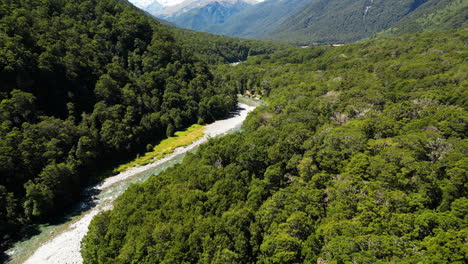 Mighty-river-surrounded-by-forest-covered-mountains-in-New-Zealand,-aerial-view