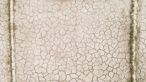 Dry-cracked-drought-fractured-land-aerial-view-rising-over-hot-barren-environment