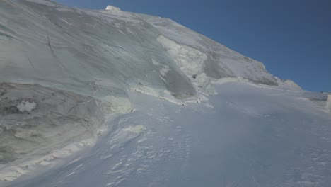 aerial-panoramic,-icy-mountain-summit-in-the-swiss-alps,-blue-sky-in-winter