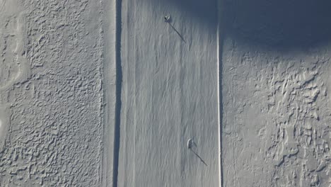 aerial-top-view-of-skiers-and-snowboarders-going-downhill-fast