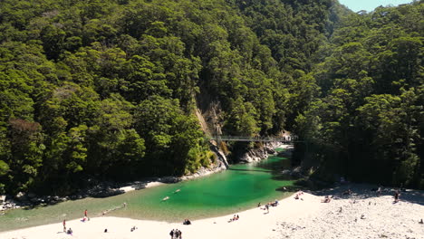 Aerial-view-of-people-bathing-on-the-beach-of-an-emerald-water-river-in-a-forest-on-a-sunny-day