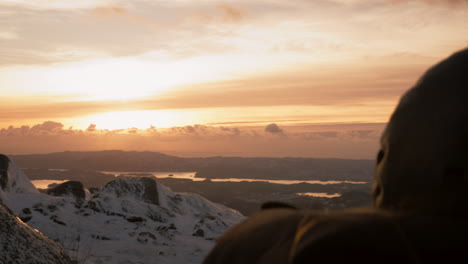 Over-the-shoulder-shot-of-a-female-enjoying-the-sunrise-views-at-Lovstakken,-Norway