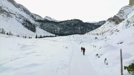 Aerial-View-Of-Couple-Hiking-Through-Snow-Path-In-Marebbe