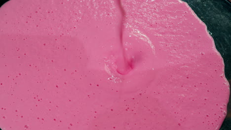 Close-up-shot-of-a-bright-pink-milkshake-being-poured-onto-a-table