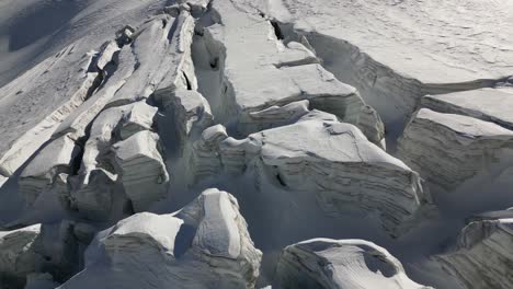 Vista-Aérea-De-Un-Montón-De-Nieve-Que-Cubre-Un-Glaciar-En-Los-Alpes-Suizos,-Invierno